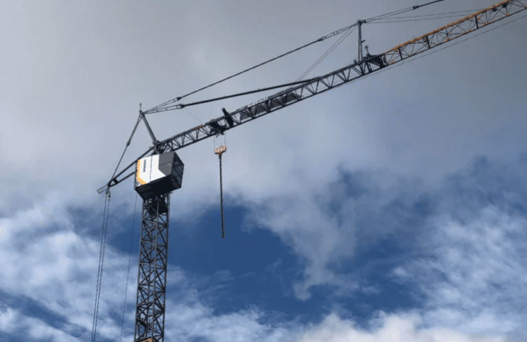 An operator in a safety vest learning to use the remote control for a self-erecting tower crane during a Bigfoot Academy training course. 
