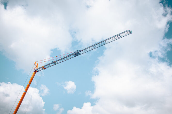 Orange construction crane against clouds