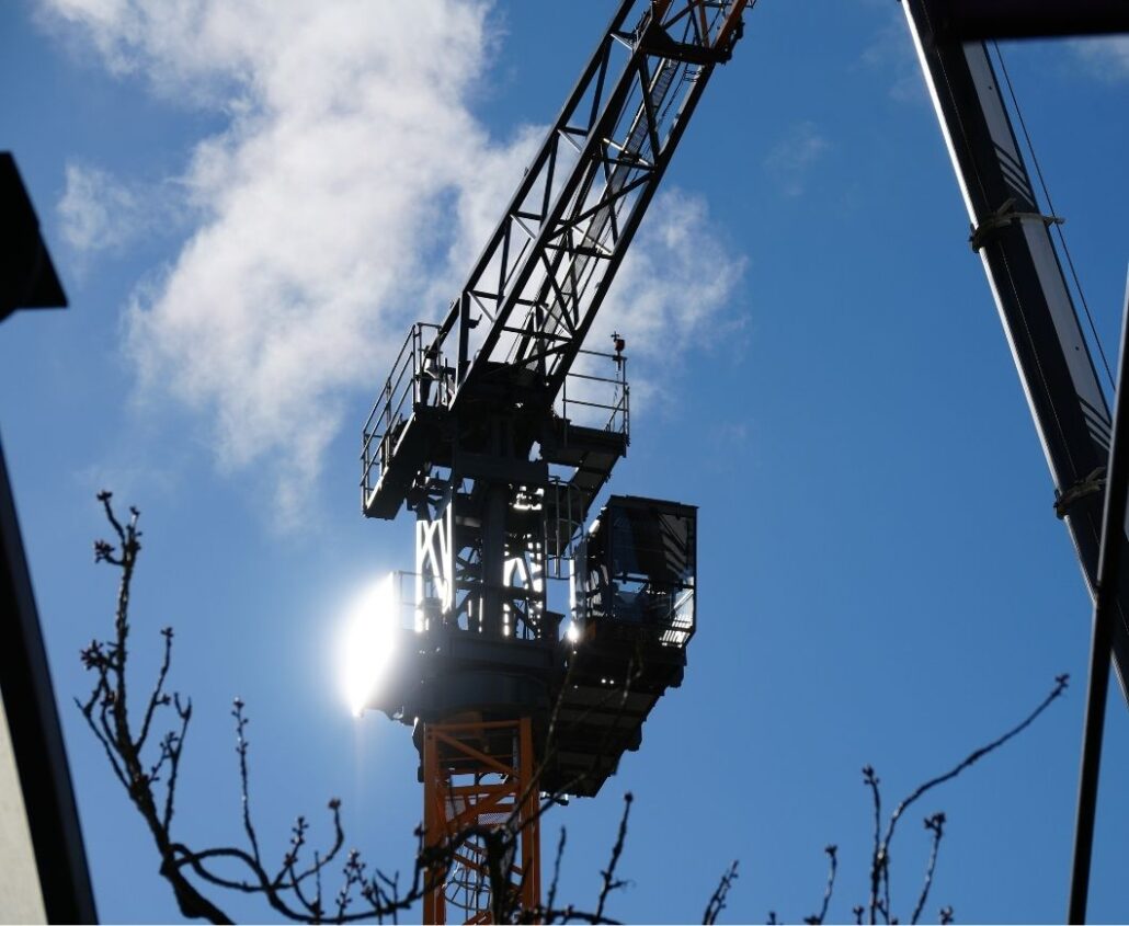 Tower crane being erected on a construction site with workers and equipment in place